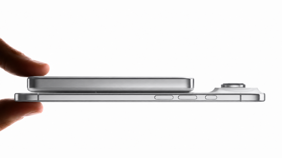 Fingers holding a silver BMX SolidSafe Air 10K snapped to the back of an iPhone, side view showing the 13mm titanium body